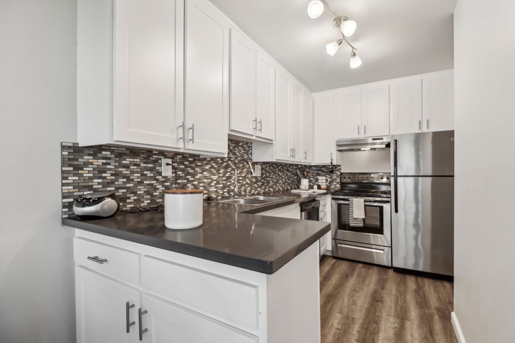 A kitchen with white cabinets and a black countertop.