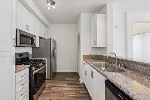 A kitchen with white cabinets and a granite countertop.