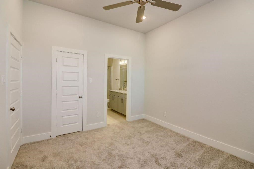 a bedroom with a ceiling fan and a door to a bathroom