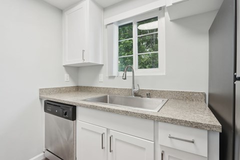 A kitchen with white cabinets and a granite countertop.