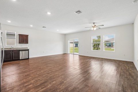 A spacious room with wooden flooring and a ceiling fan.