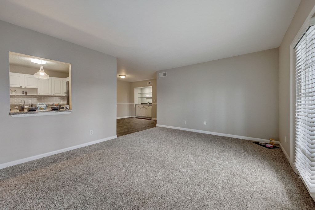 Pet-Friendly Apartments in Sandy Springs – Celebration at Sandy Springs - an empty living room with a window and a kitchen
