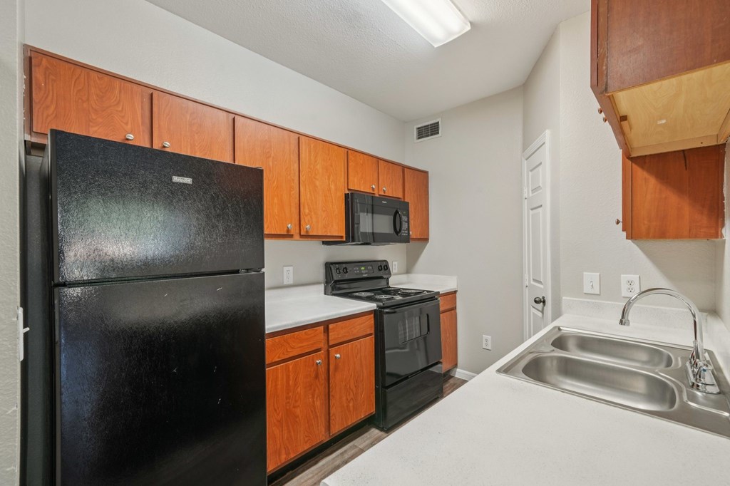 A kitchen with black appliances and wooden cabinets.