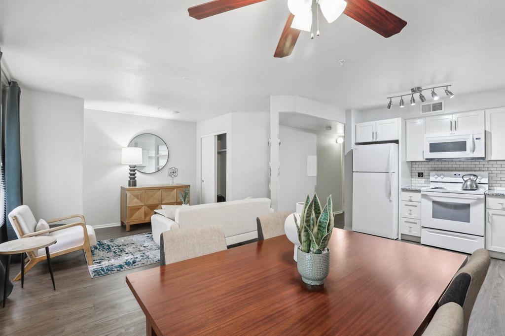 A modern kitchen with white appliances and a wooden table.