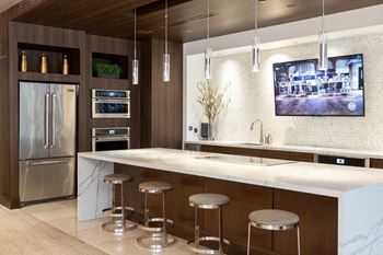 Apartments In Sandy Springs, GA for Rent – Arabelle Perimeter –a kitchen with a bar and stools and a television in the clubhouse