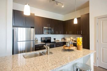 Apartments In Sandy Springs, GA for Rent – Arabelle Perimeter –a kitchen with a granite counter top and a stainless steel refrigerator