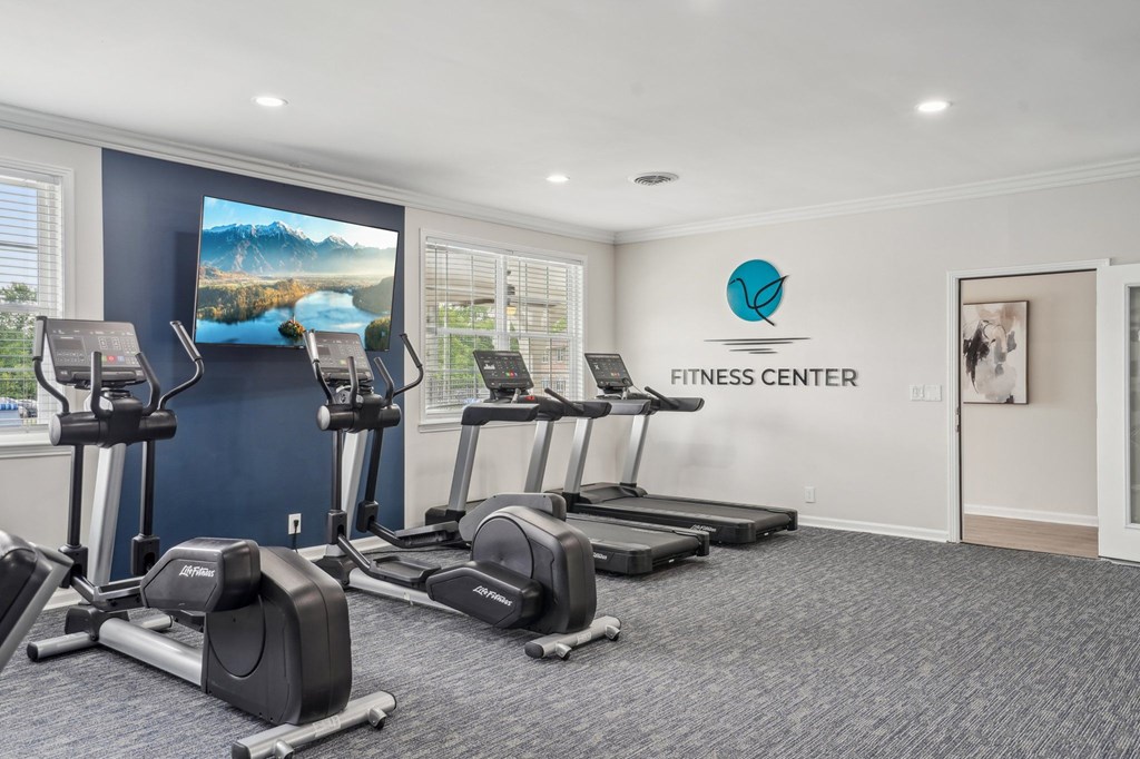Fitness center with treadmills, elliptical machines, and a wall-mounted television.