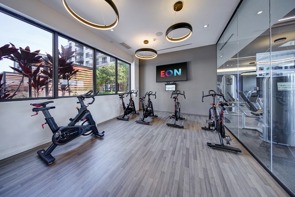 a gym with exercise bikes on the floor and a large window