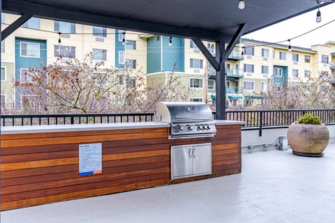 A BBQ grill is on a wooden deck with a sign on it.