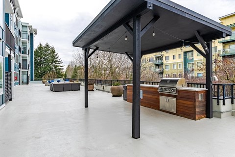 A patio with a grill and a black awning.