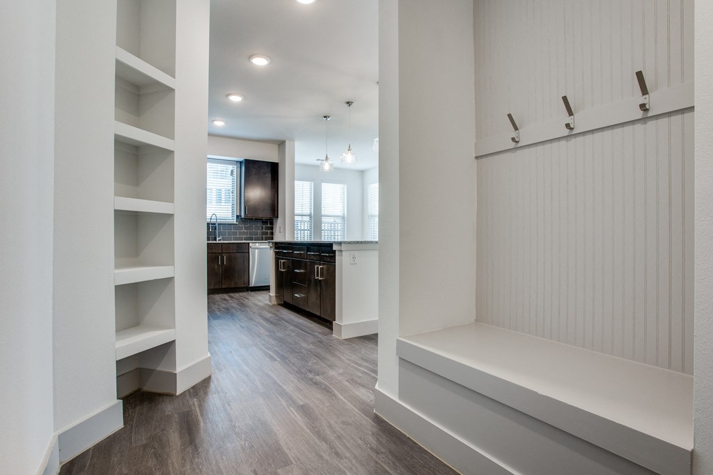 a bedroom with a medium hardwood floor and a white closet with white shelves