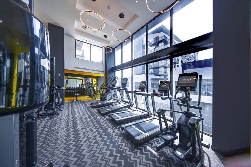 a gym with cardio equipment and windows in a building