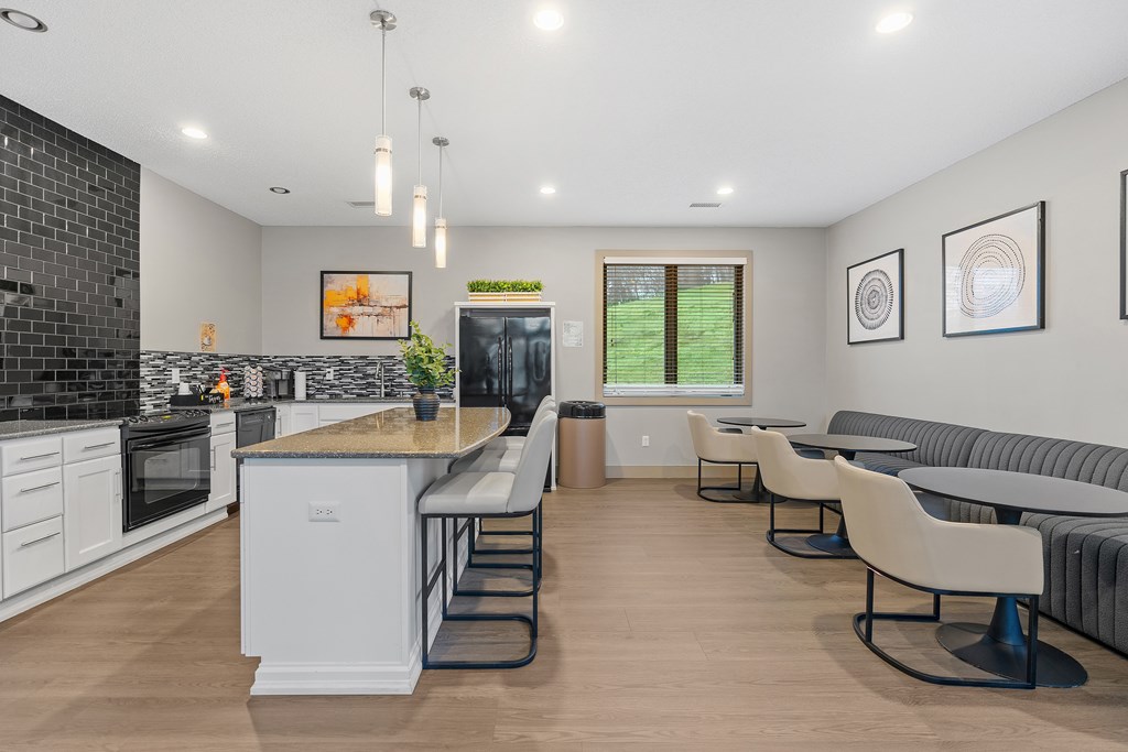 A modern kitchen with a large island and a dining area with grey couches.