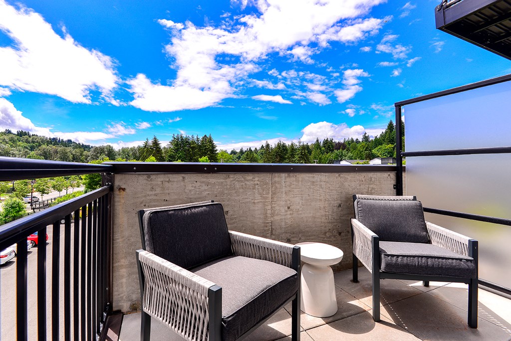 a balcony with two chairs and a table and a blue sky