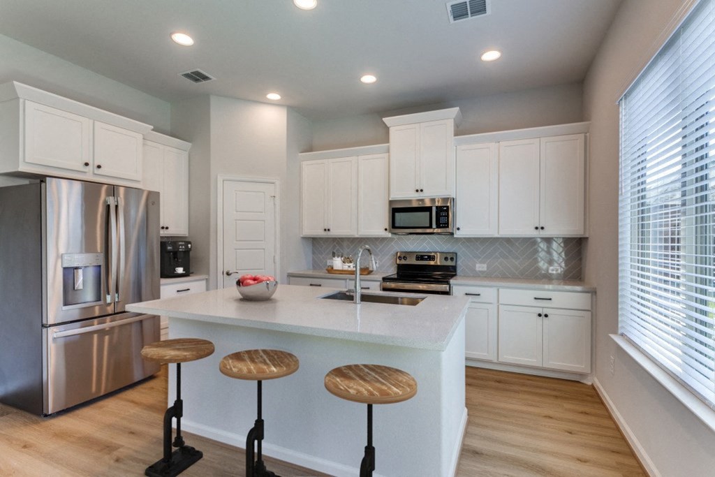 A modern kitchen with white cabinets and stainless steel appliances.