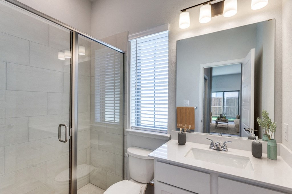 A bathroom with a toilet, sink, and mirror.