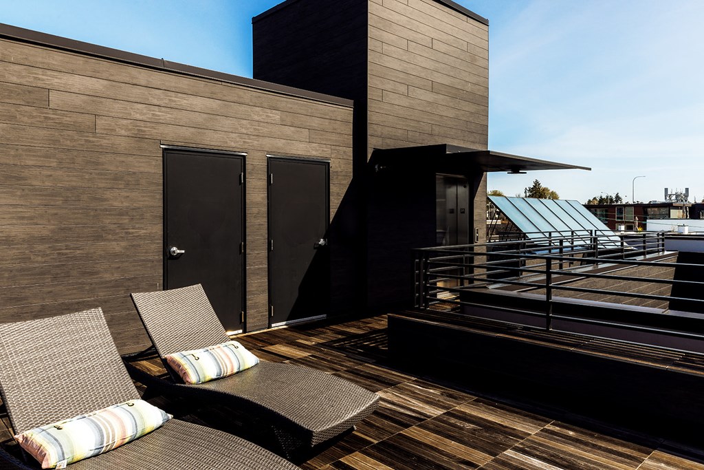 a roof deck with two chairs and a view of a building