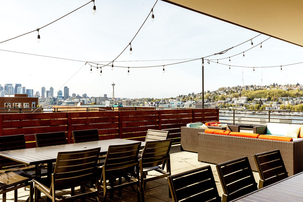 a roof deck with tables and chairs and a view of the city