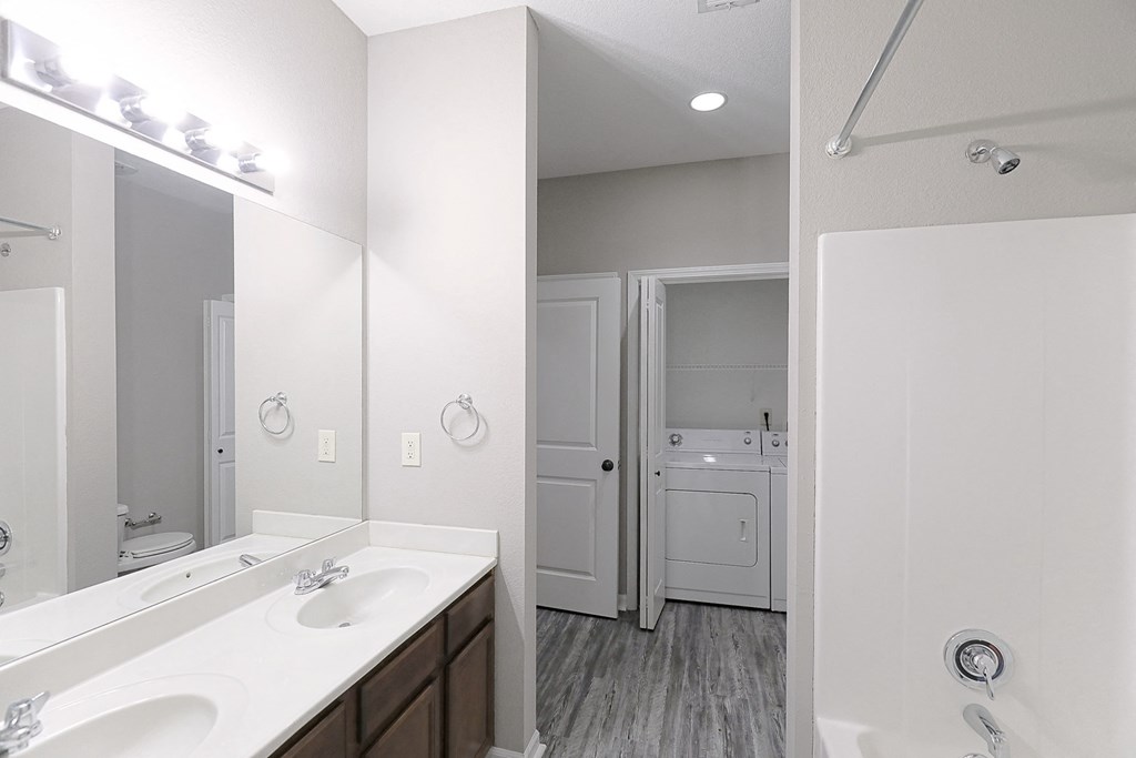 a bathroom with two sinks and a mirror and a laundry room