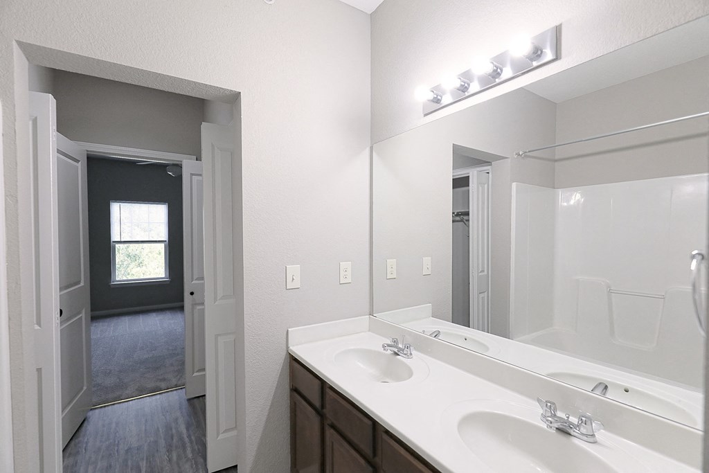 an empty bathroom with a large mirror and two sinks