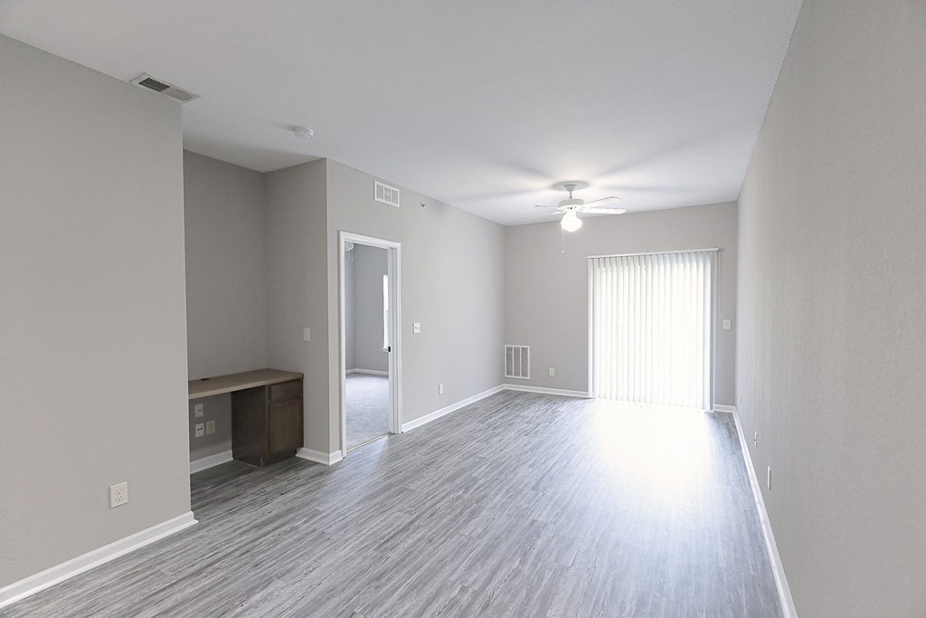 an empty living room with wood flooring and a ceiling fan