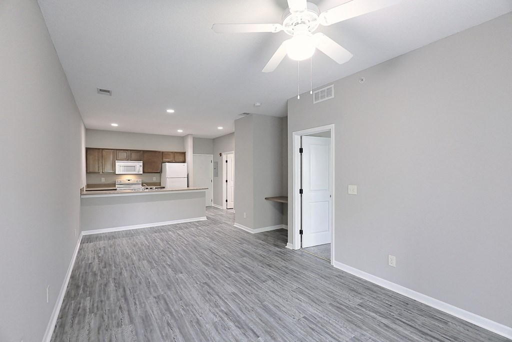 an empty living room and kitchen with a ceiling fan