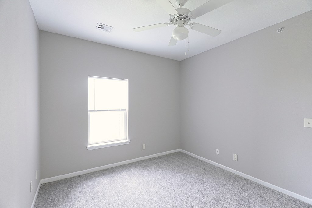 an empty room with a ceiling fan and a window