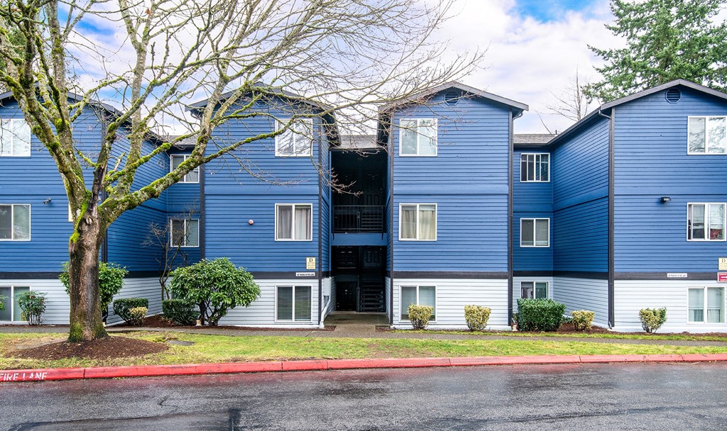 a row of blue and white apartment buildings with a red curb