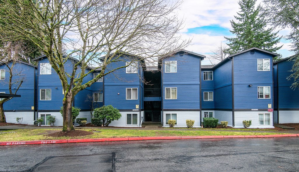 a row of blue and white apartment buildings with a red curb