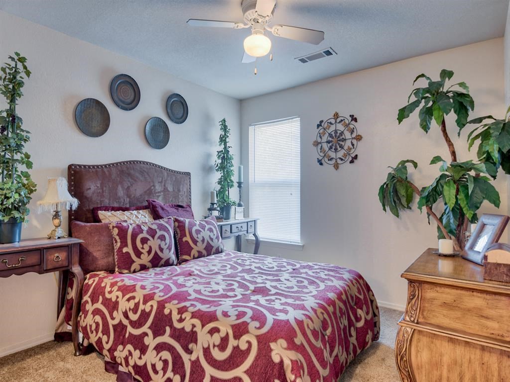 Bedroom with carpet floor, queen size bed, ceiling fan, and window with shades