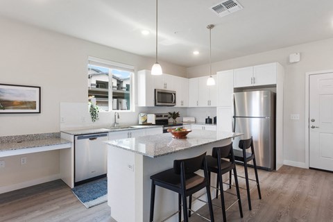 a kitchen with an island with stools and a stainless steel refrigerator