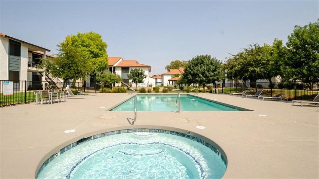 a resort style pool with chaise lounge chairs and apartment buildings in the background