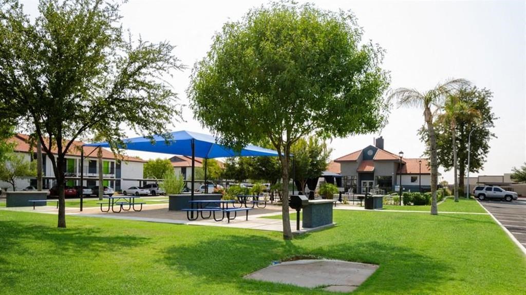 a park with tables and umbrellas and houses in the background