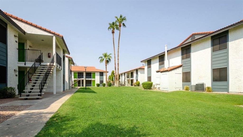 a grassy area with a staircase and palm trees in the background