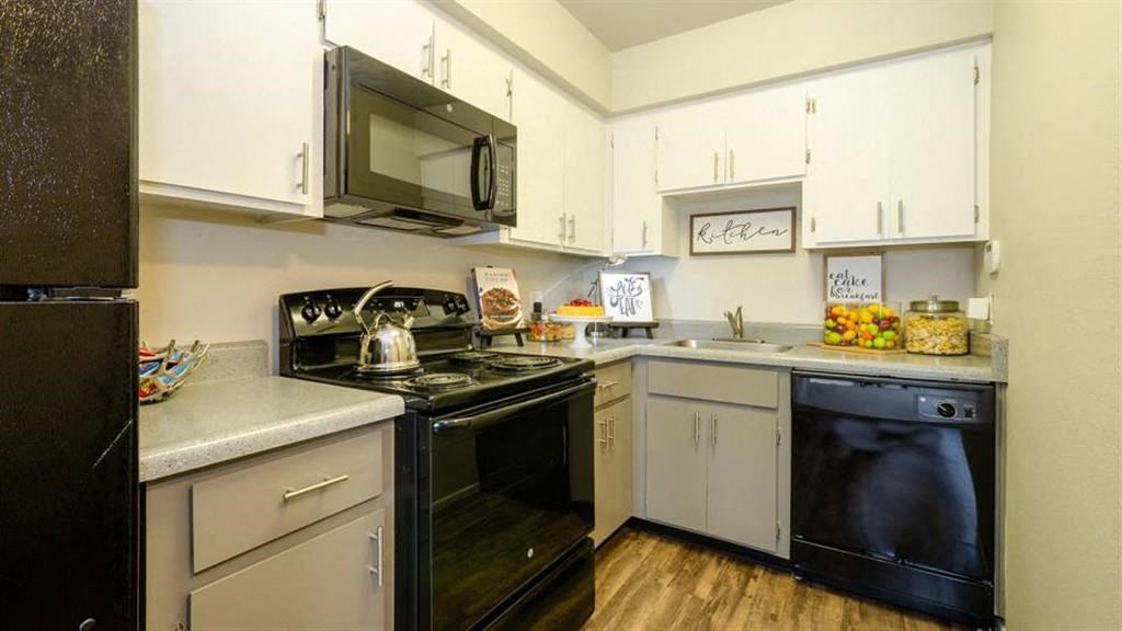 Apartments for Rent Mesa, AZ - Mesa Station - L-Shaped Kitchen with White and Grey Cabinetry, Black Appliances, and Granite-Style Countertops