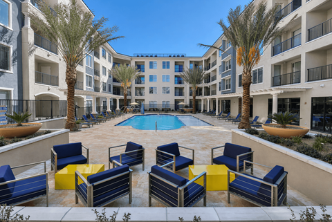 A pool surrounded by blue chairs and palm trees.