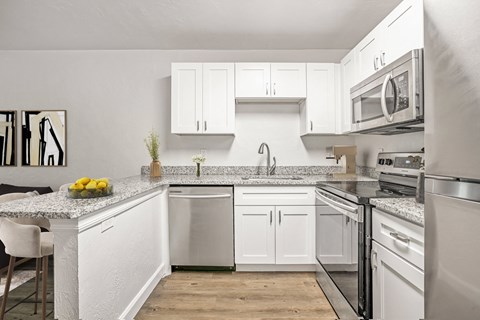 a white kitchen with stainless steel appliances and granite counter tops