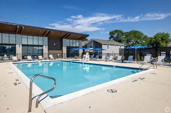 A large swimming pool with a diving board and a building in the background.