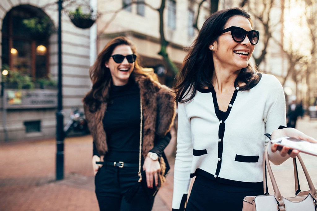 two women walking down the street with shopping bags