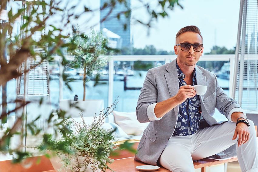 a man wearing a suit and sunglasses holding a coffee cup