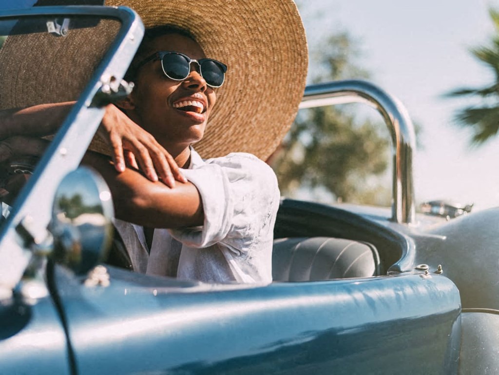 a man sitting in a convertible car with a hat