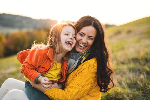 a mother and daughter laughing in a field