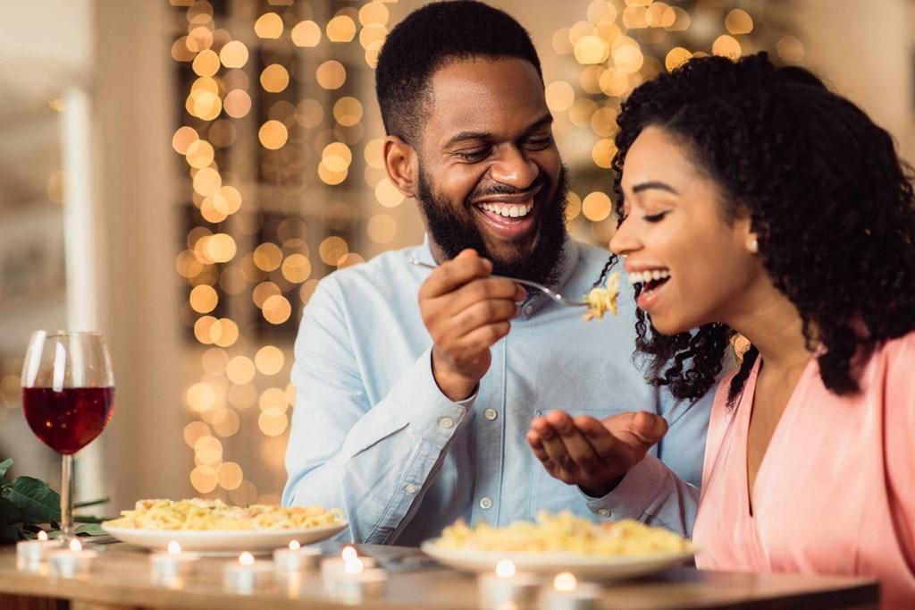 a man and woman sitting at a table eating food together