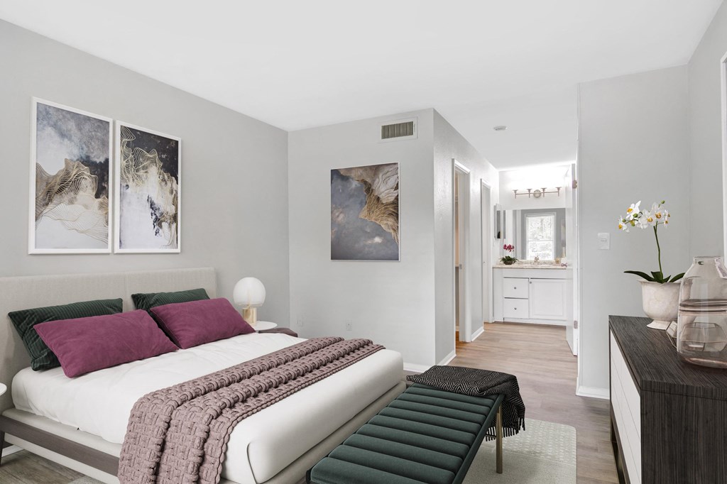 Affinitee at Stone Mountain Apartments photo of a bedroom with a bed with purple pillows and a green bench