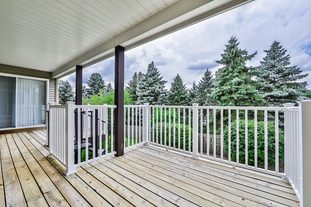 the spacious deck has a view of the trees and the water