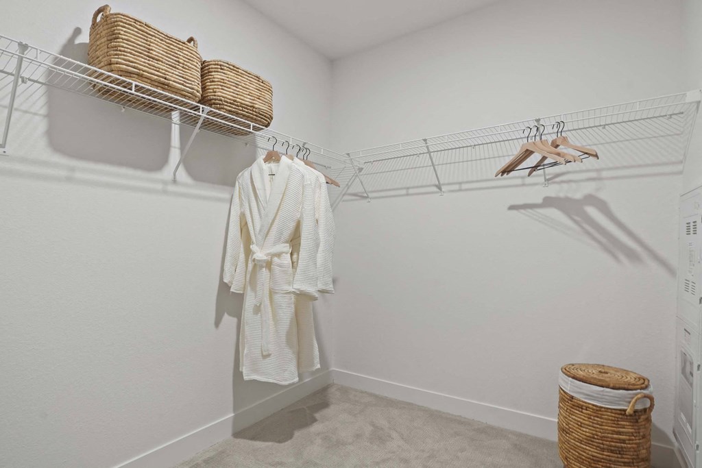 a walk in closet with a white robe and shoe rack
