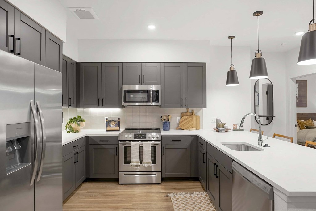 a kitchen with gray cabinets and stainless steel appliances