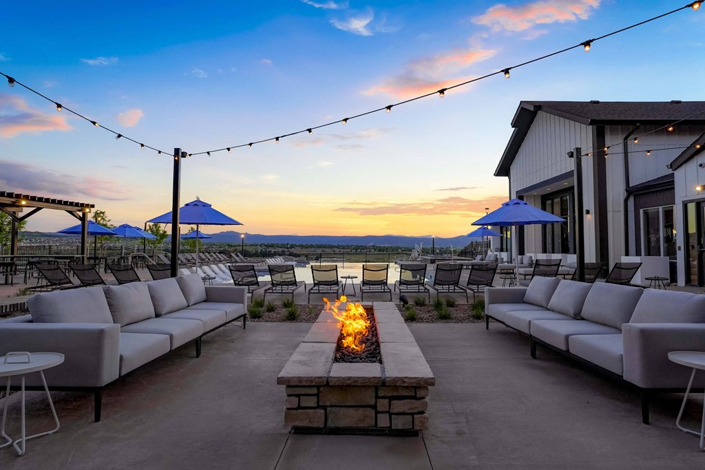 a patio with couches and chairs and a fire pit at dusk