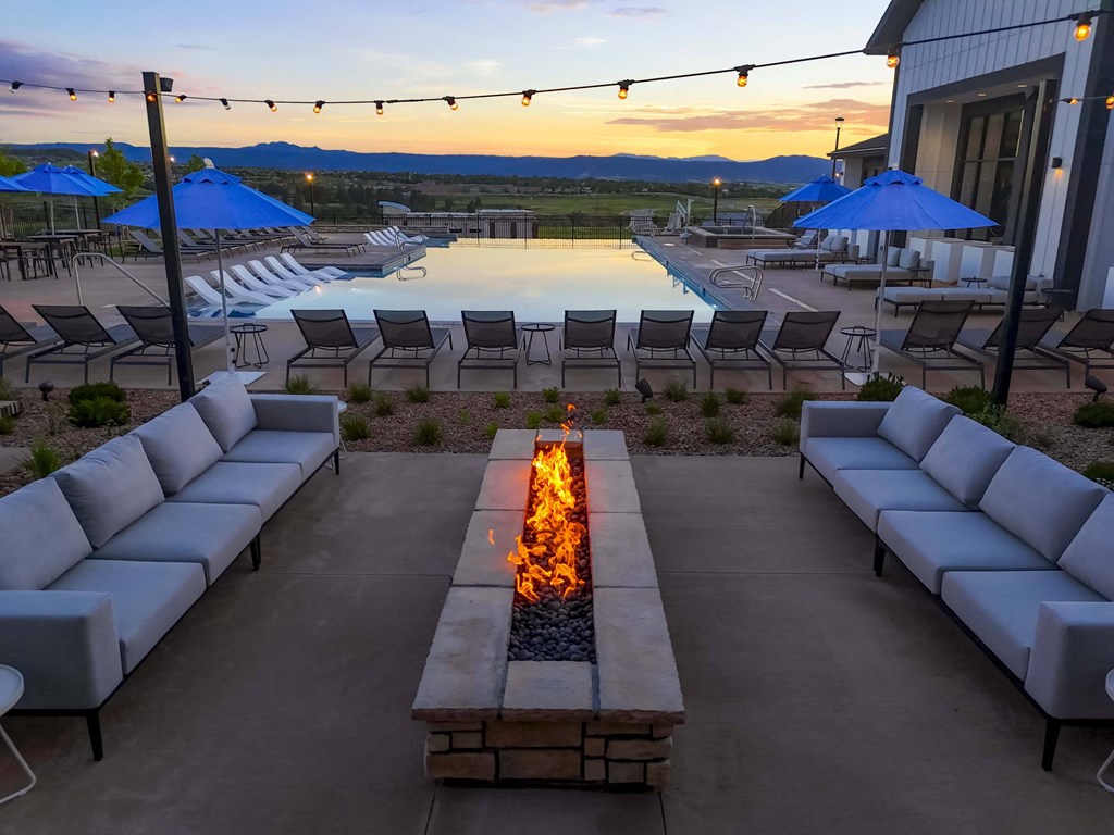 a lounge area with couches and chairs around a fire pit