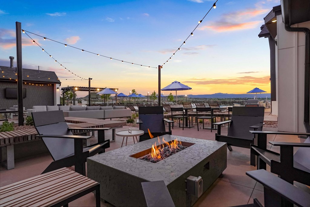 a fire pit on the patio of a restaurant with tables and chairs